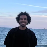 Mohamed smiling on a beach at dusk
